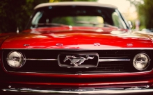 Решетка радиатора и значок на красном Ford Mustang крупным планом